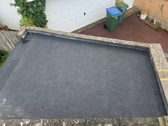 Storm Dry Roofing: the finished garage flat roof seen from above, new felt dressed up to the coping all round