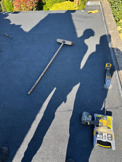 Storm Dry Roofing flat roof job, after: new grey mineral felt laid across the same roof and dressed up to the edge