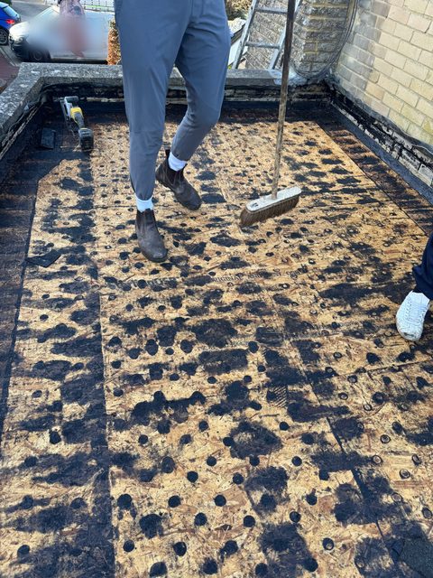 Storm Dry Roofing flat roof job, before: the old felt stripped back to the timber deck inside the parapet walls
