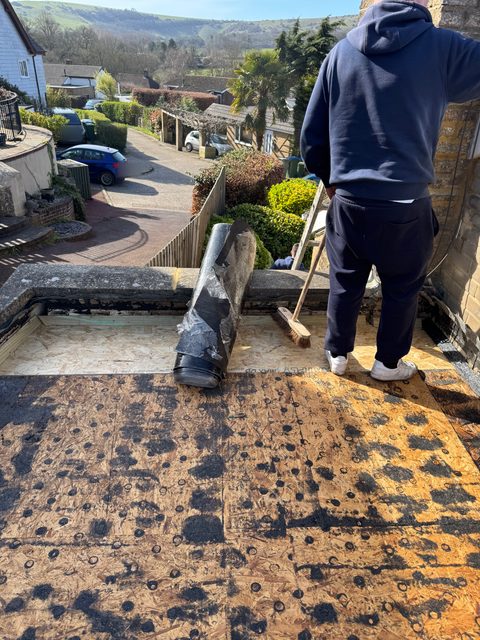 Storm Dry Roofing flat roof job: the old felt rolled up and cleared off the deck at the front edge