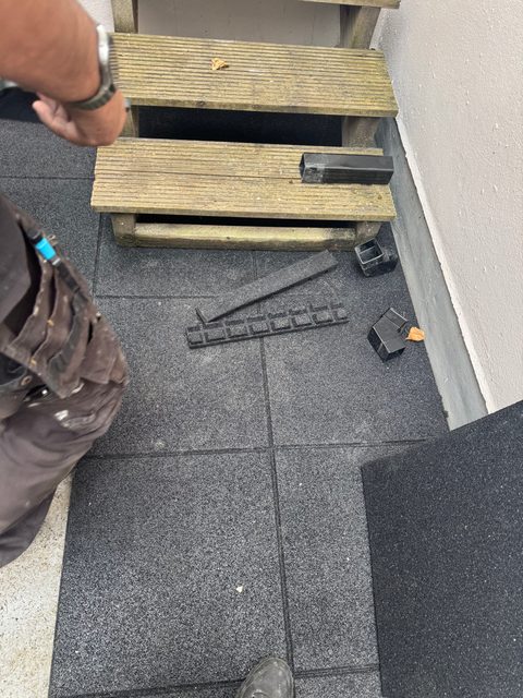 Storm Dry Roofing flat roof terrace: rubber tiles on pedestals being laid up to a set of timber steps