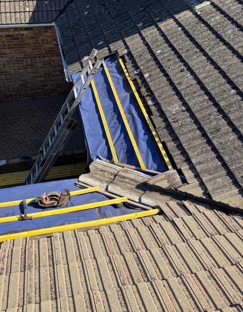 Storm Dry Roofing re-roof: new blue membrane and yellow battens fixed on a section of a concrete-tiled roof