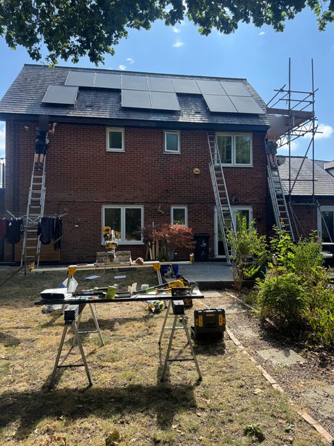 Storm Dry Roofing team working at the eaves of the same brick house from a ladder and a scaffold tower
