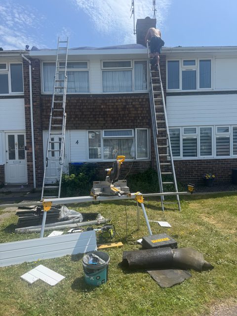 Storm Dry Roofing uPVC fascia job, during: ladders up the front of a terraced house while the old roofline comes off
